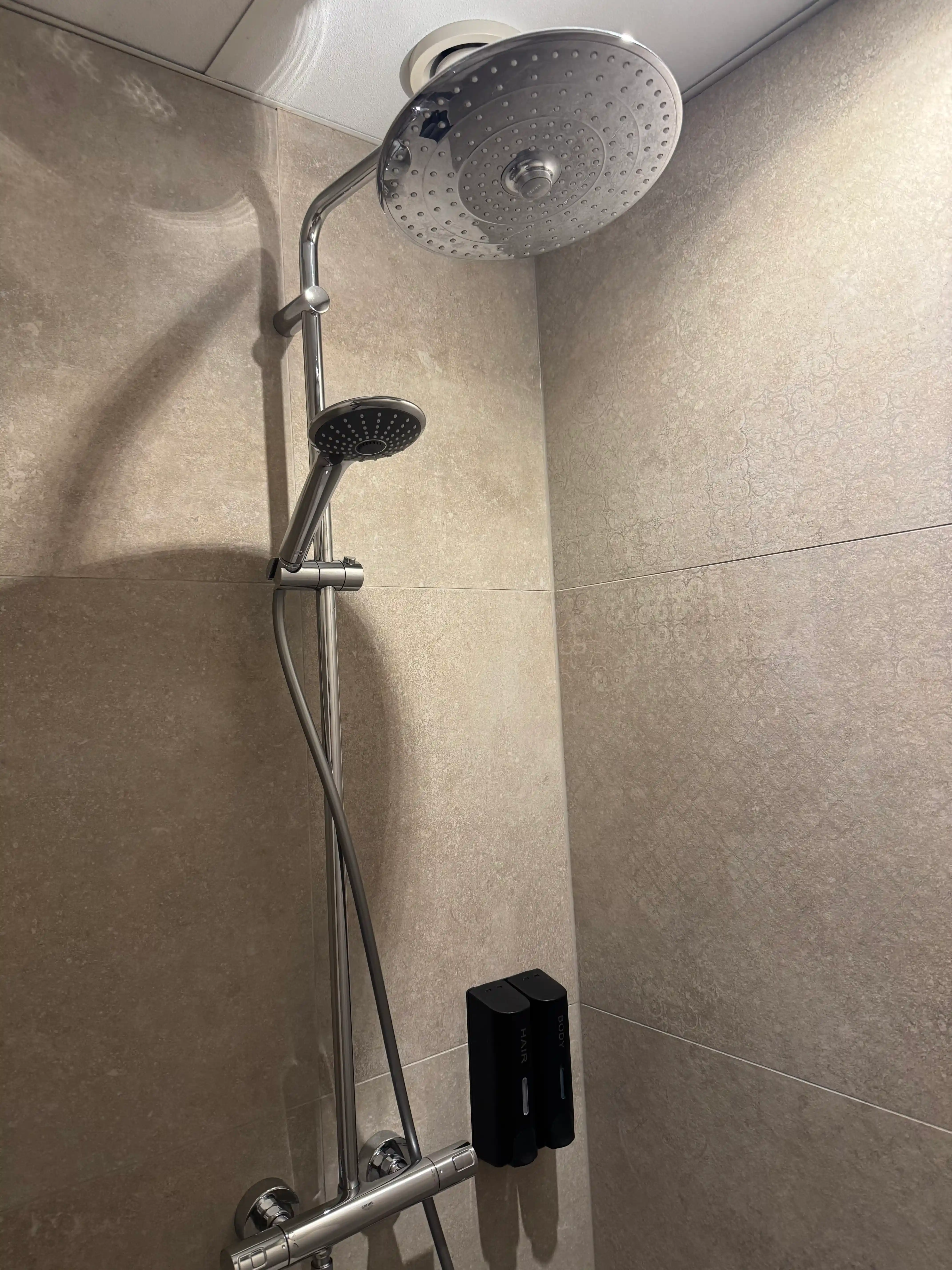 Luxe regendouche met beige tegels in modern appartement.