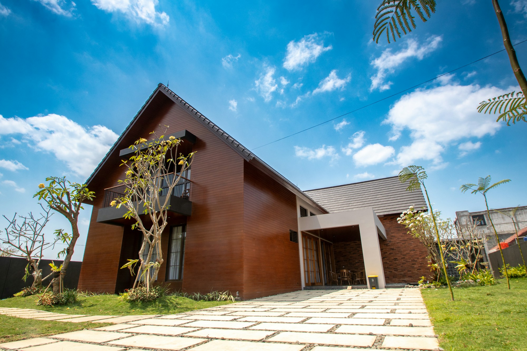 Modern wooden vacation home with a paved driveway under a blue sky