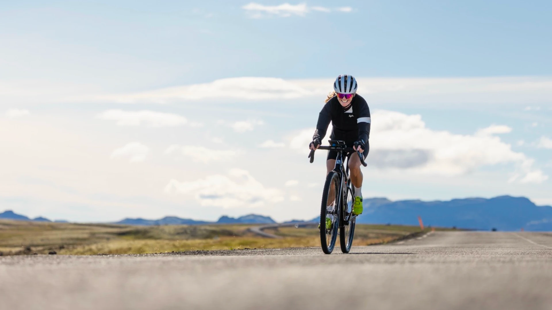 one smiling woman rides her bike on a sunny day
