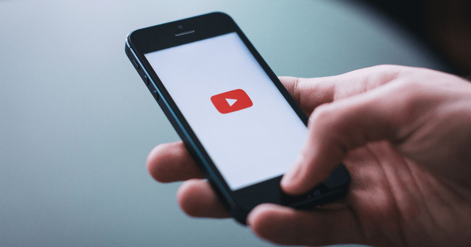 Hand holding smartphone displaying YouTube logo - YouTube Hooks