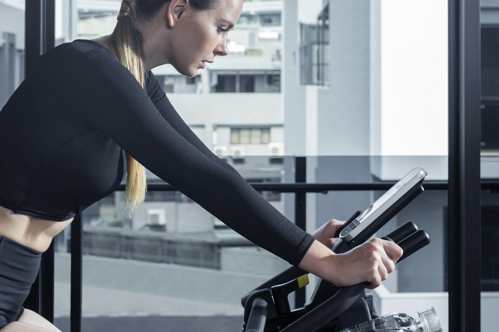 Woman on a stationary bike consulting a tablet device