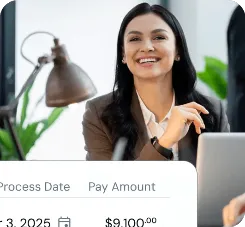 A person holding a laptop and smiling indoors.