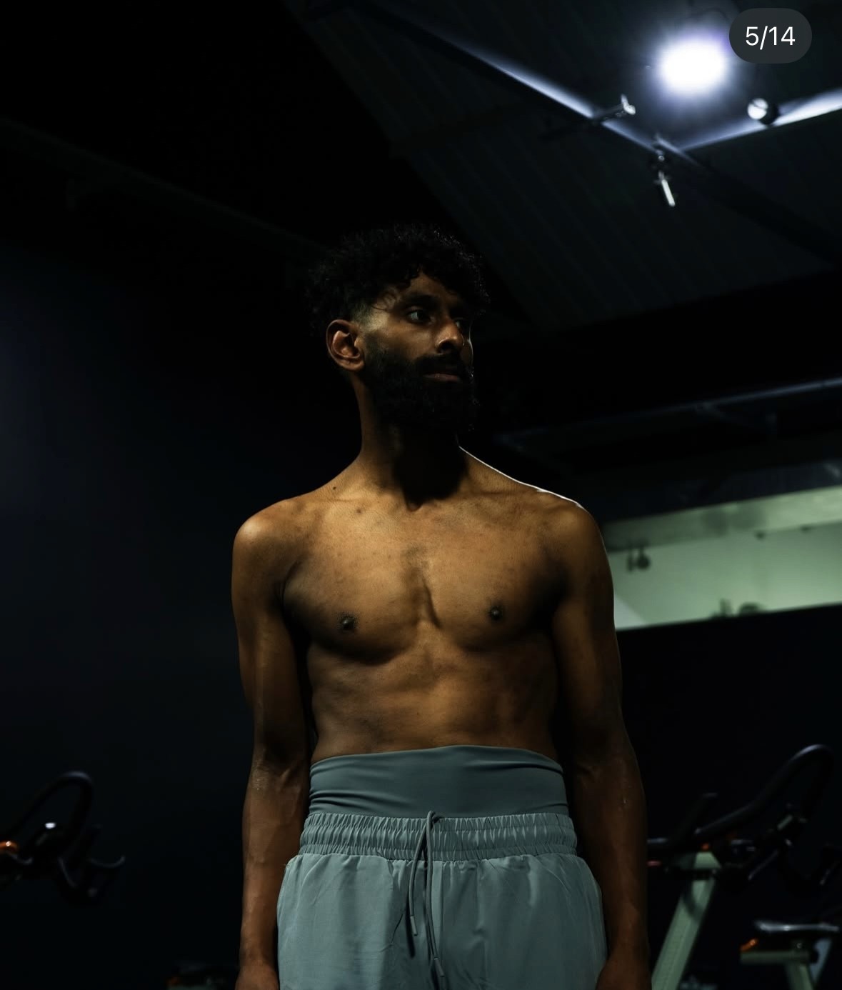 Full-body portrait of a male athlete standing in a gym during a performance fitness photoshoot.