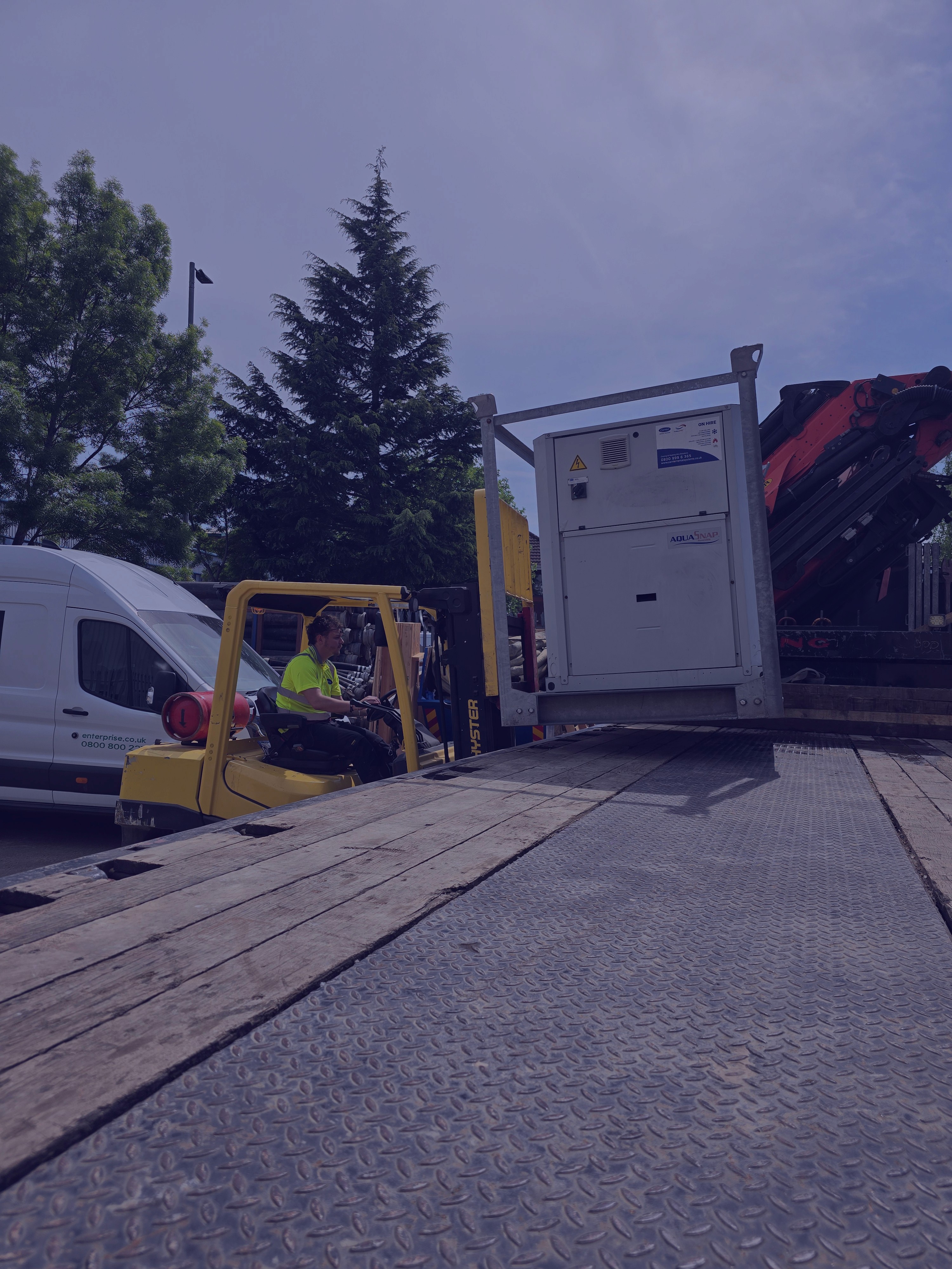 Image of a forklift unloading a heavy object off of a flatbed trailer
