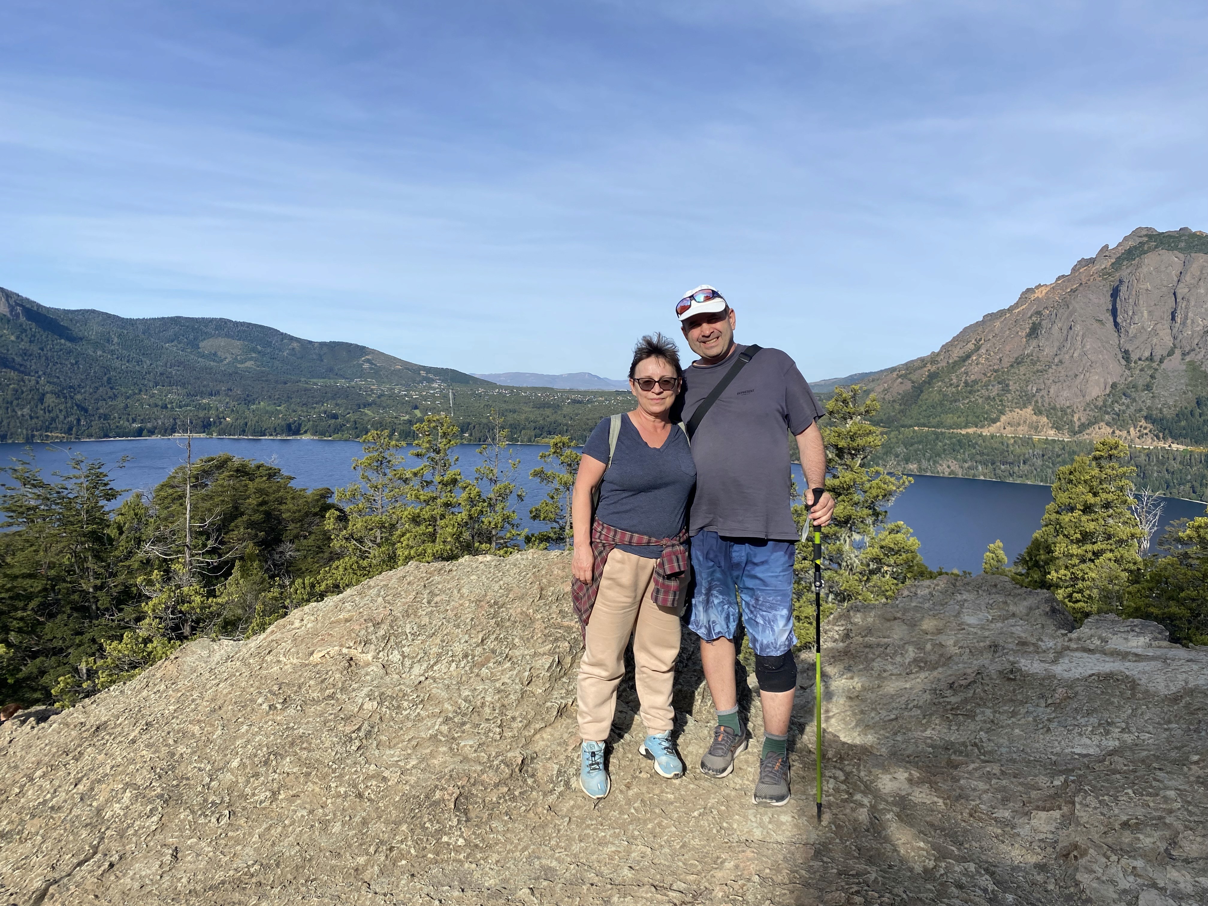 Mujer sentada sobre un tronco frente a una cascada doble en un bosque frondoso de Argentina.
