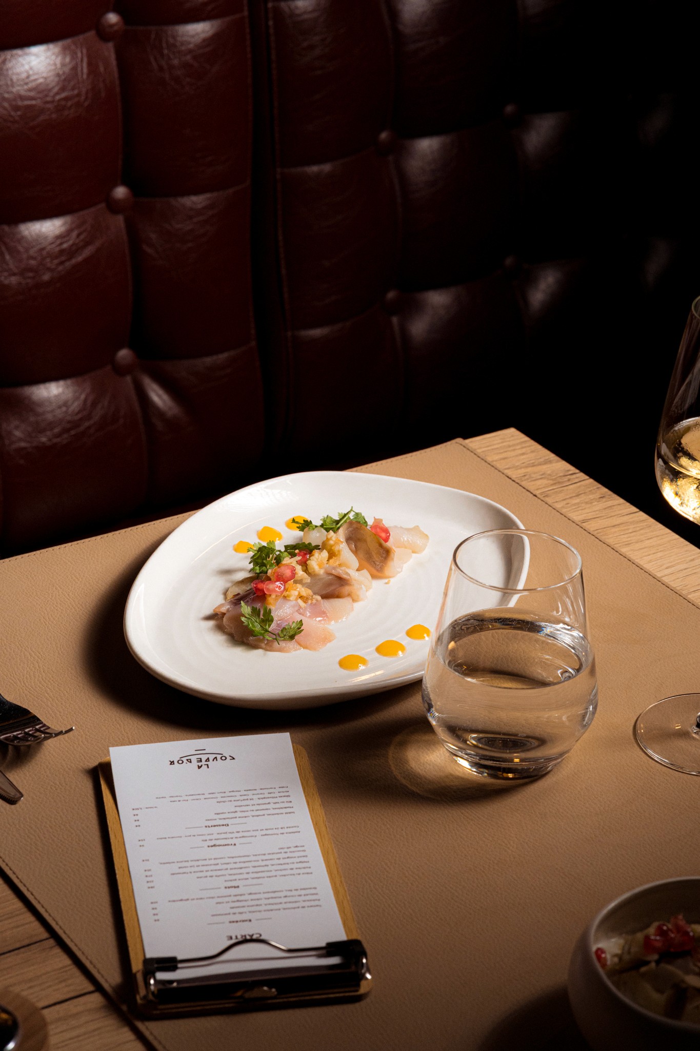 Assiette élégante de gravelax de lieu poisson cru et condiments colorés, représentant l’approche gastronomique et raffinée du restaurant à Vichy.