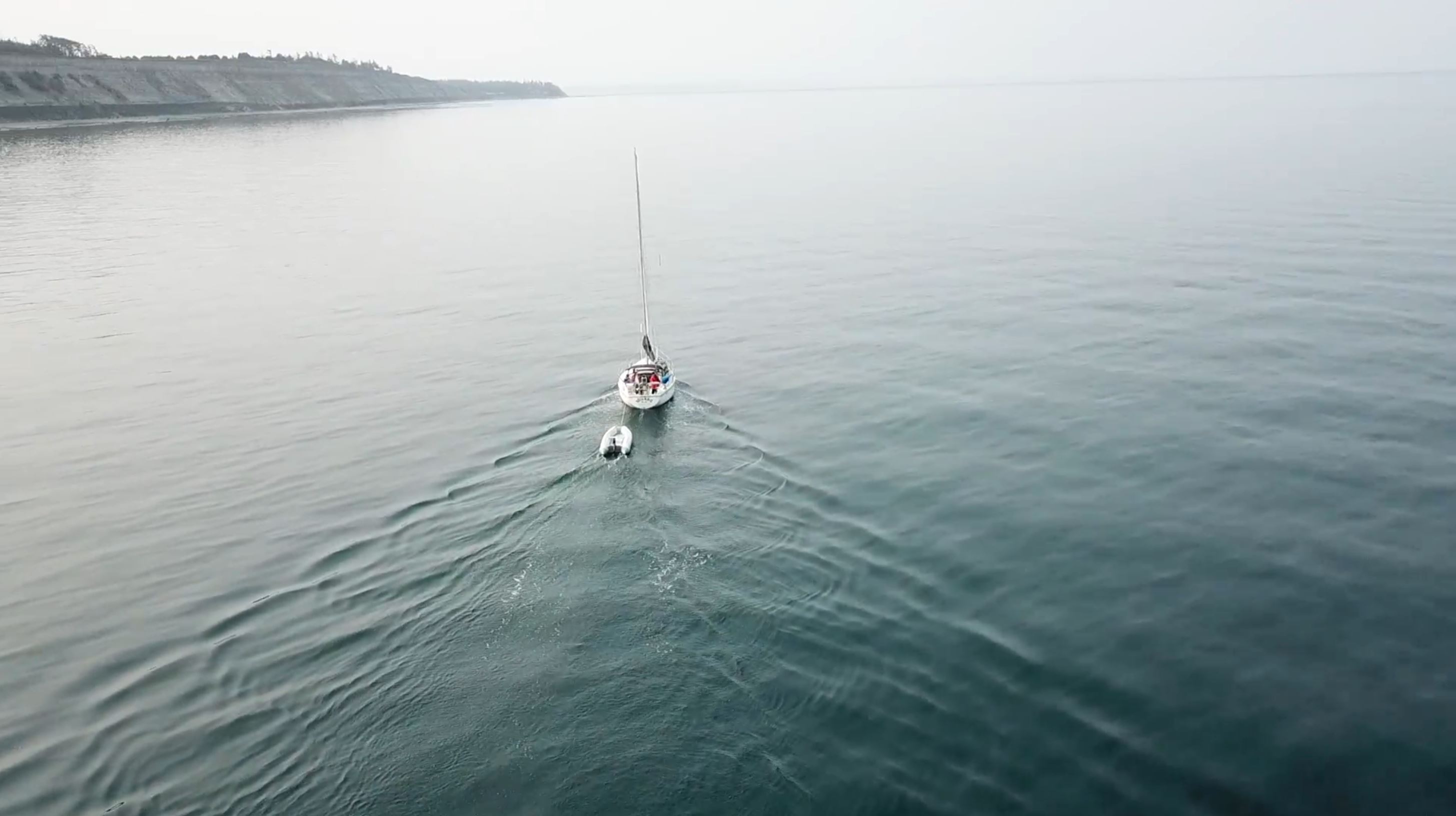 Three people in conversation with warm lighting, including a person wearing a hat and another person wrapped in what appears to be a textured shawl or sweater.