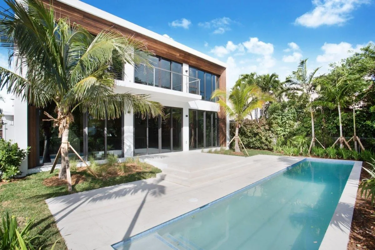 Rear view of modern Miami Beach home with lap pool and floor-to-ceiling glass
