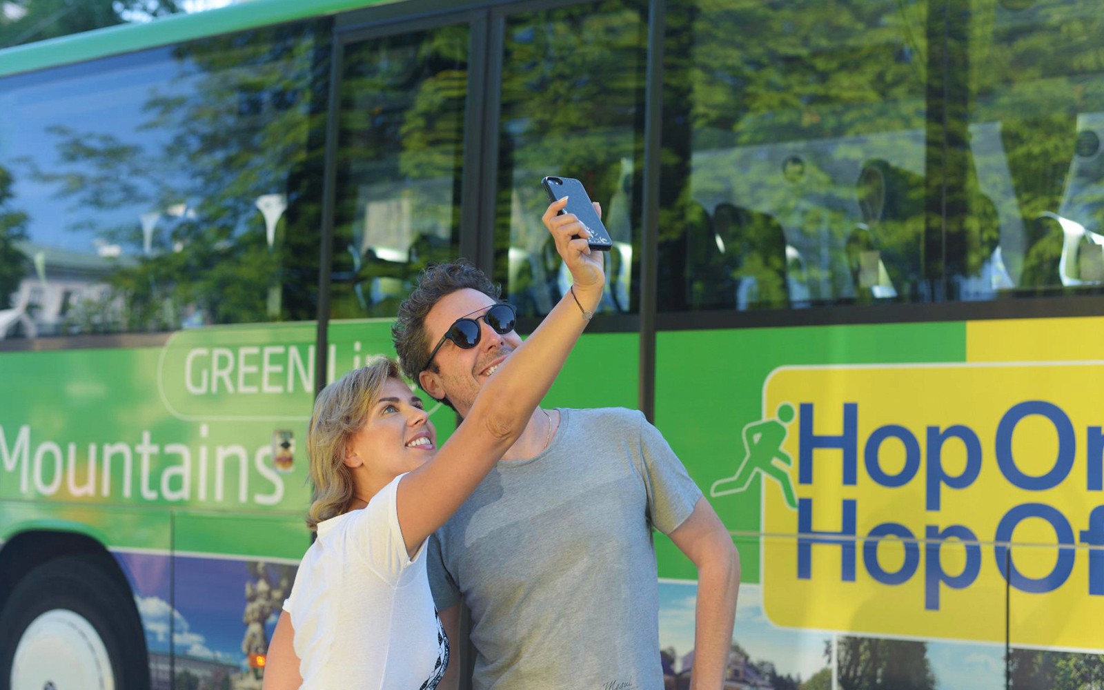 Turister tager en selfie foran en Hop On Hop Off-bus i Salzburg.