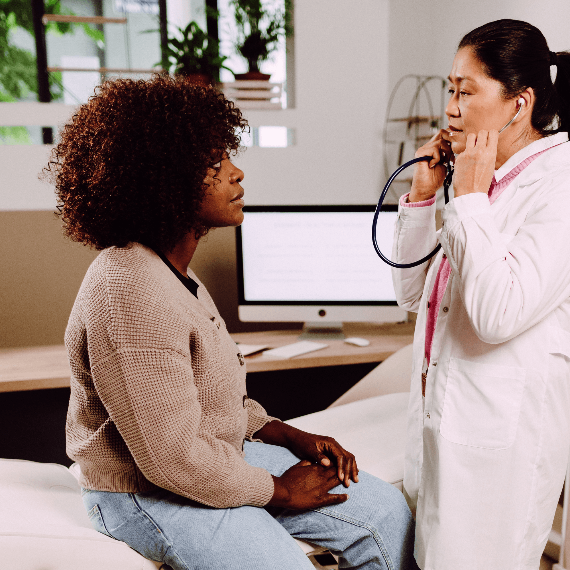 Female doctor listening to a young woman’s heart during a medical examination.