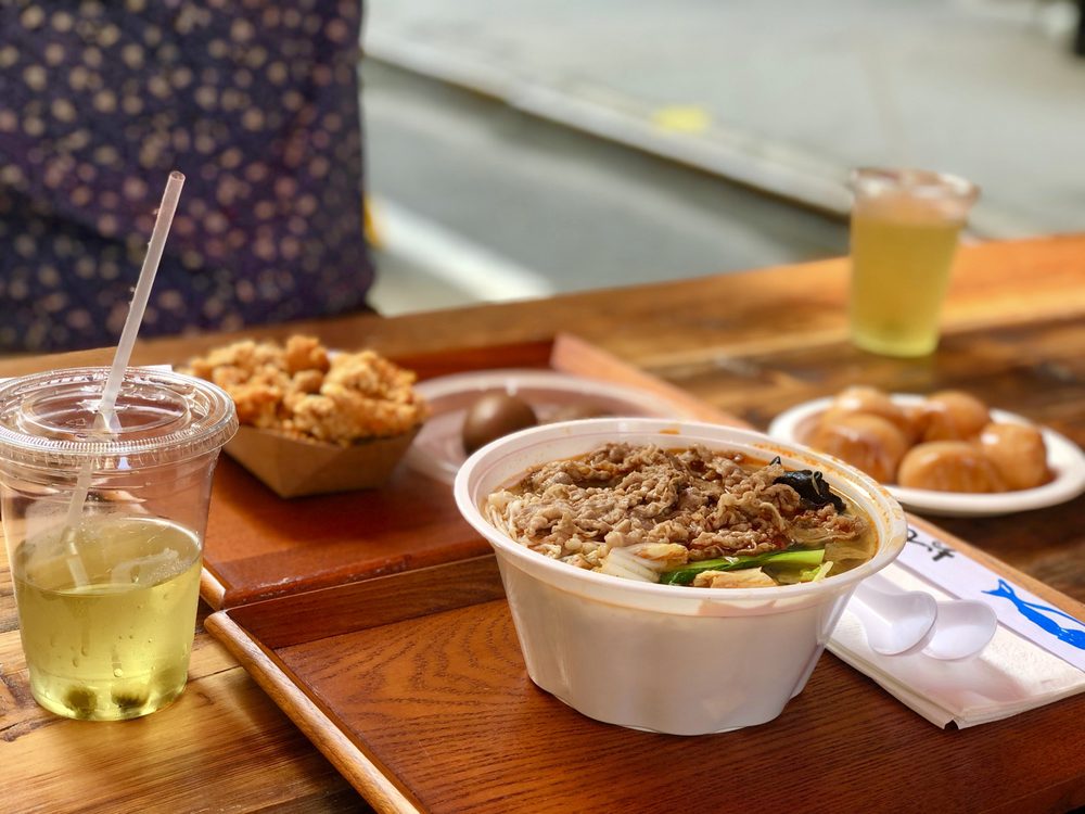 A bowl of Bao Bao Cafe’s dan dan noodles, topped with a rich, nutty sauce and garnished with fresh scallions and chili flakes.