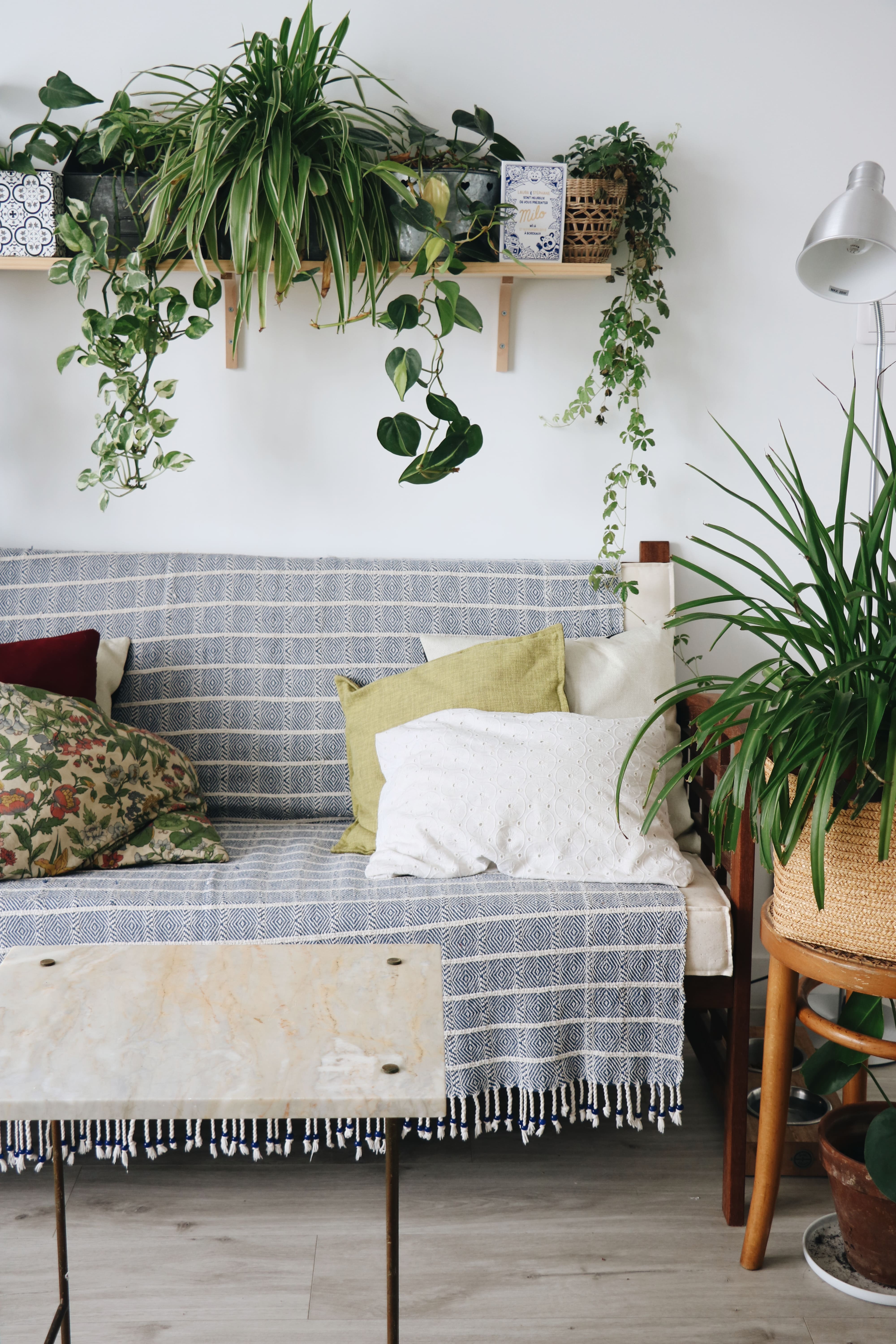 Coin salon avec banquette, table en marbre chinées et plantes