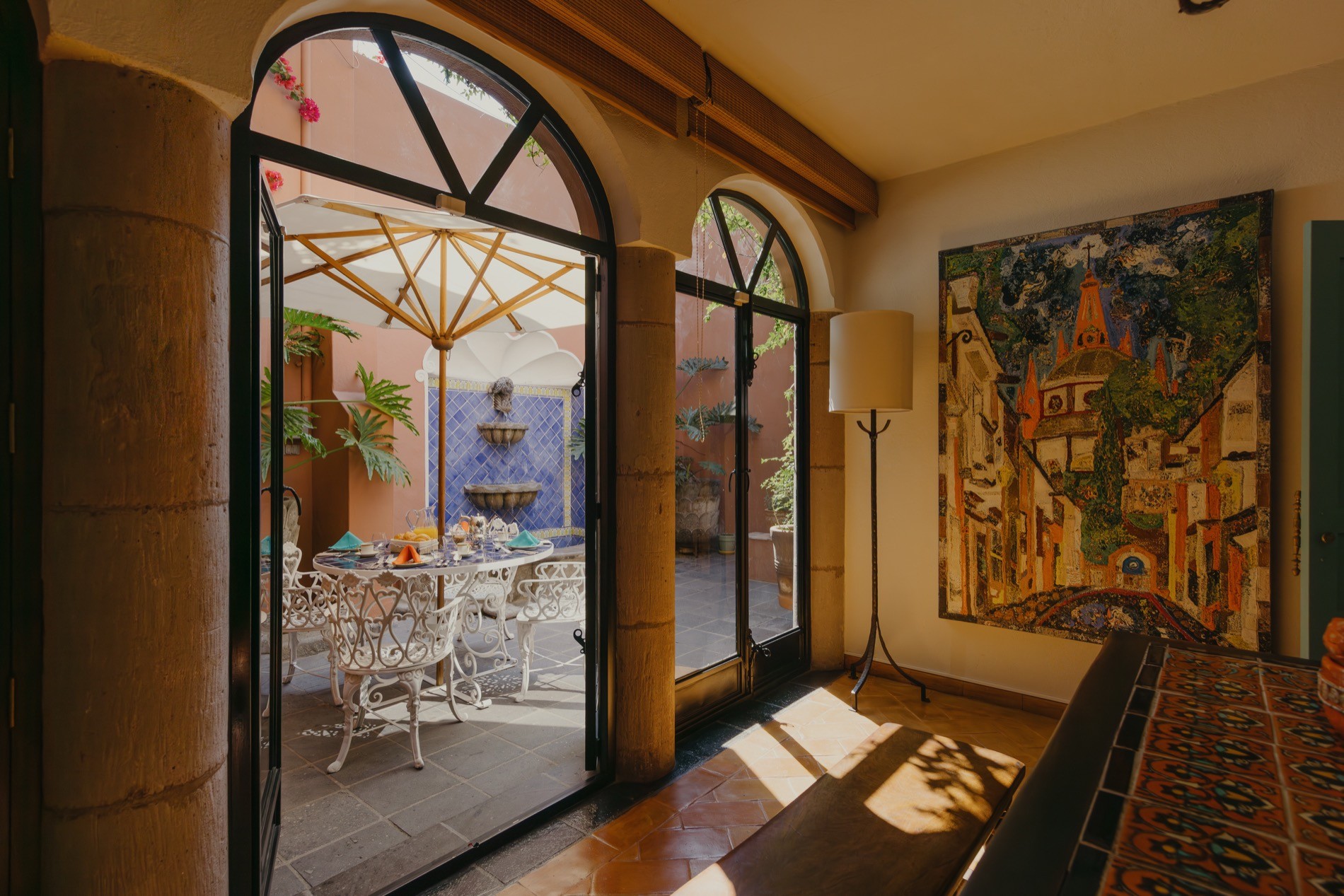 La Residencia courtyard dining with fountain, arched doors, and San Miguel de Allende artwork