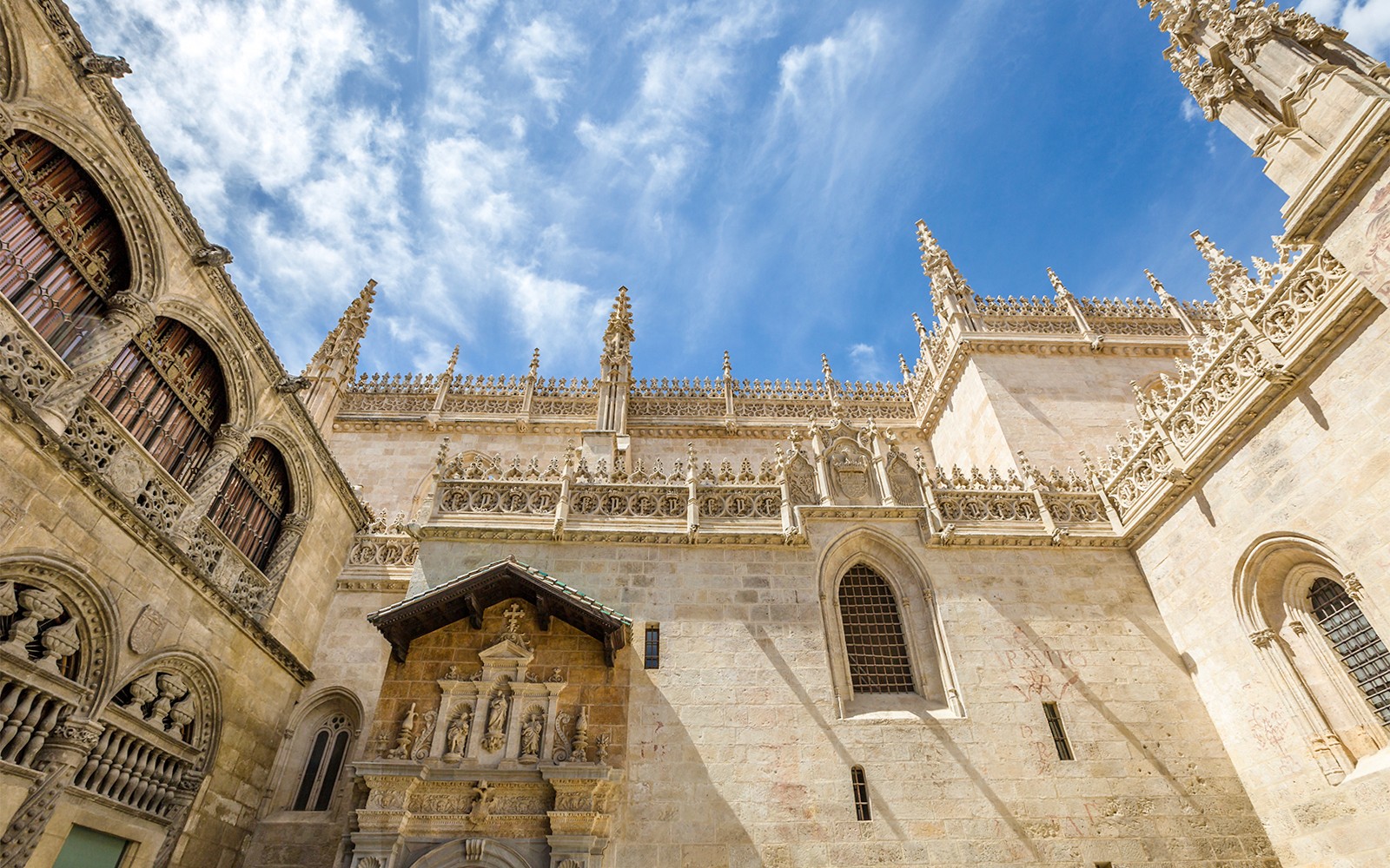 Esterno della Cappella Reale di Granada con ornata architettura gotica sotto un cielo azzurro.