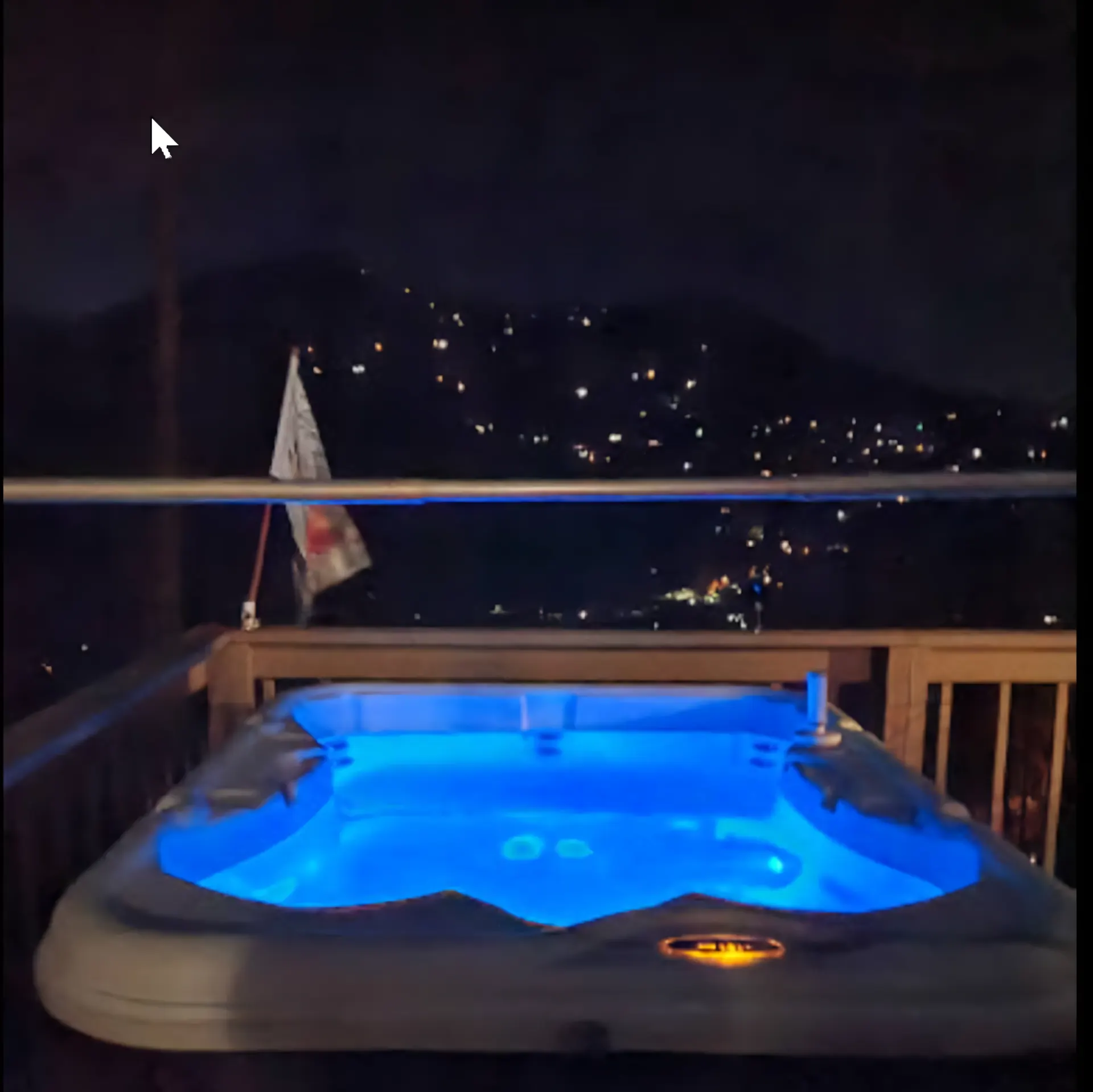 Bella Vista hot tub lit blue at night with town lights across the valley