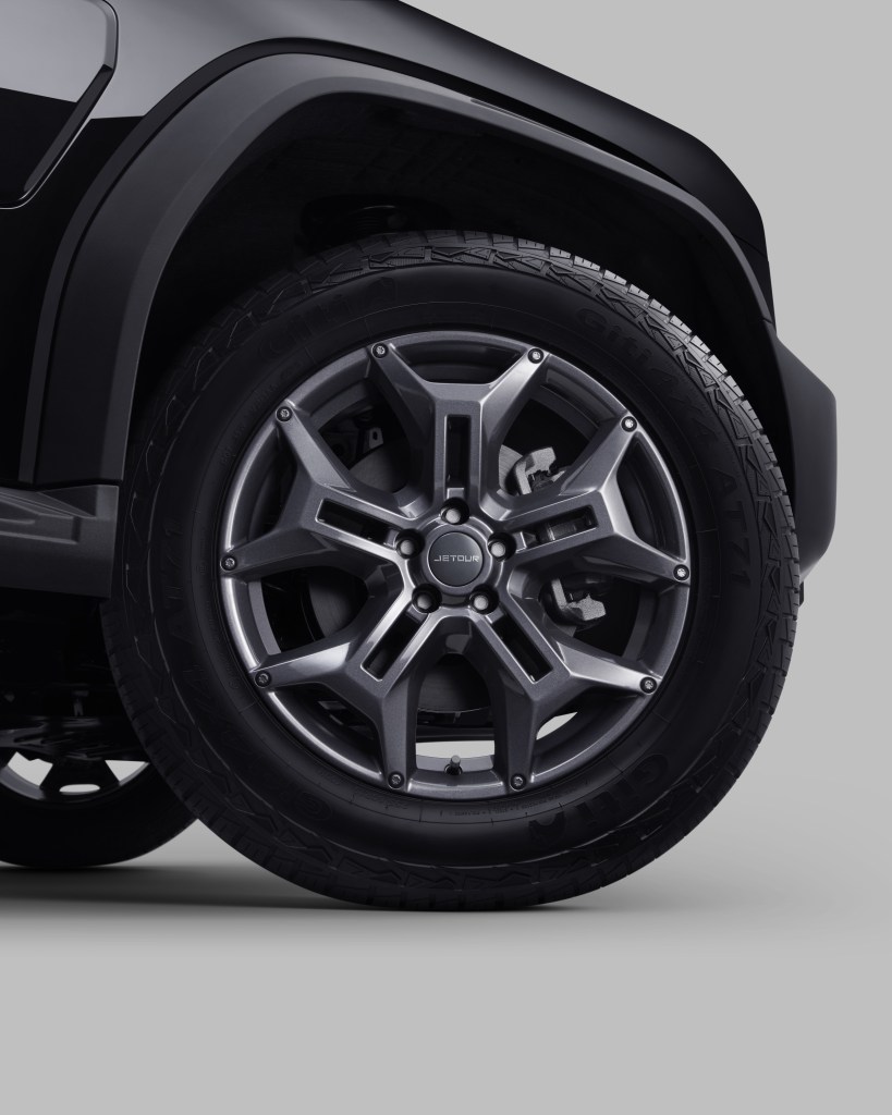 Close-up image of a black SUV's wheel and tire, highlighting a stylish metallic wheel design and robust tread pattern.