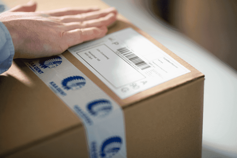 Person touching package with KAA Gent branded tape 