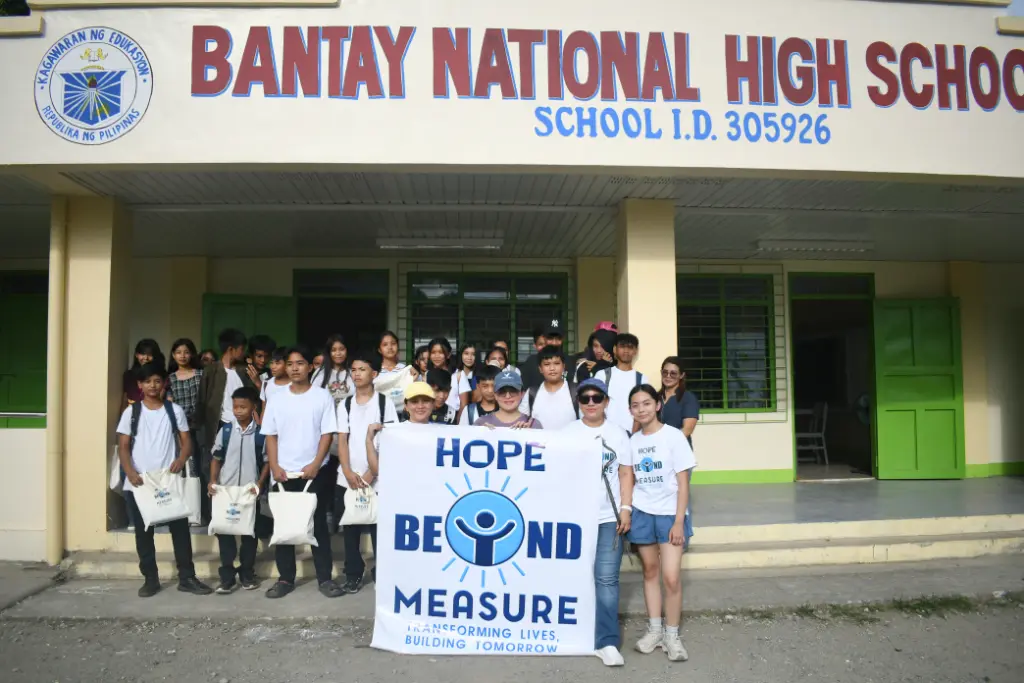 Students holding the Hope Beyond Measure banner in front of Bantay National High School