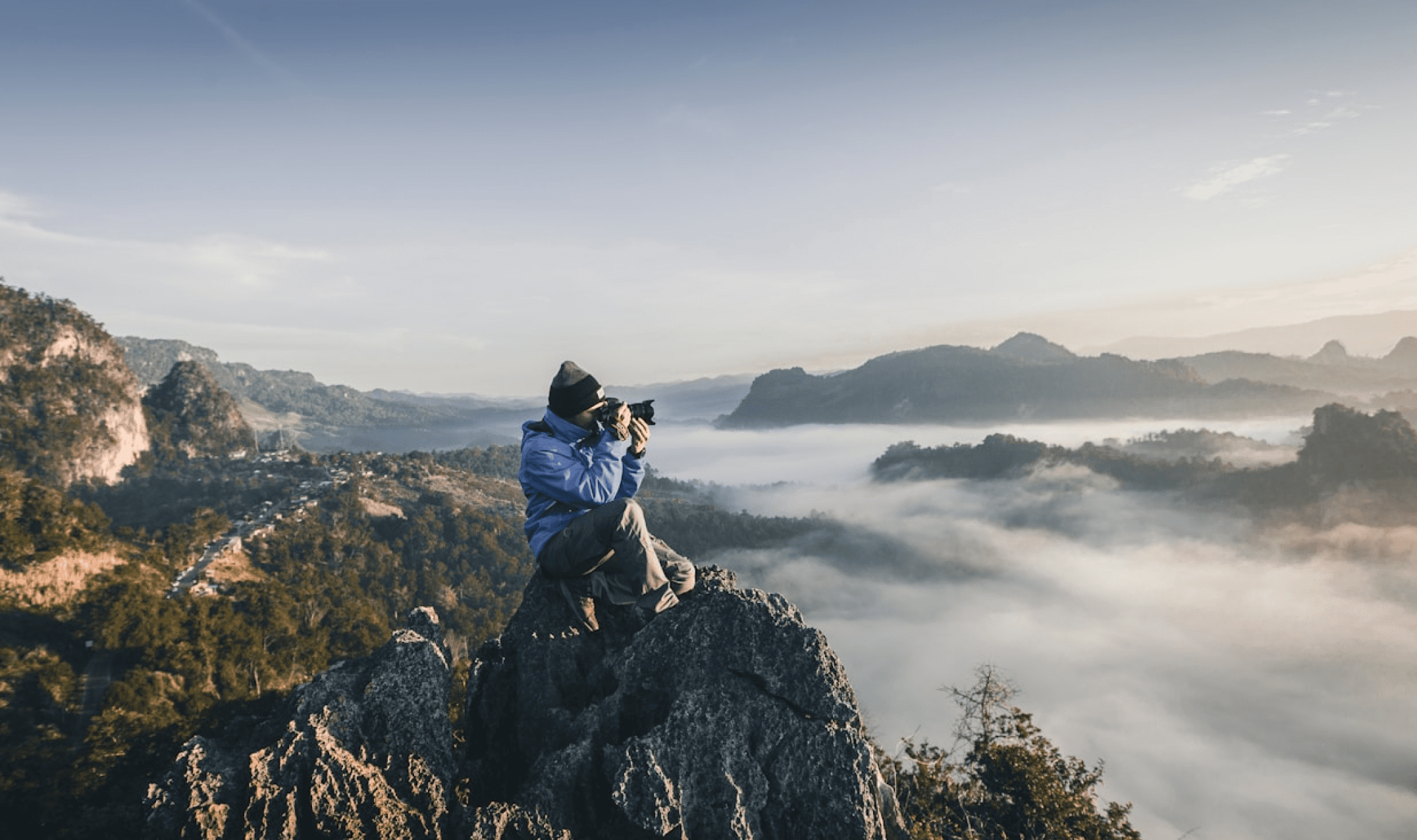 Photographer man sitting at the top of a rock