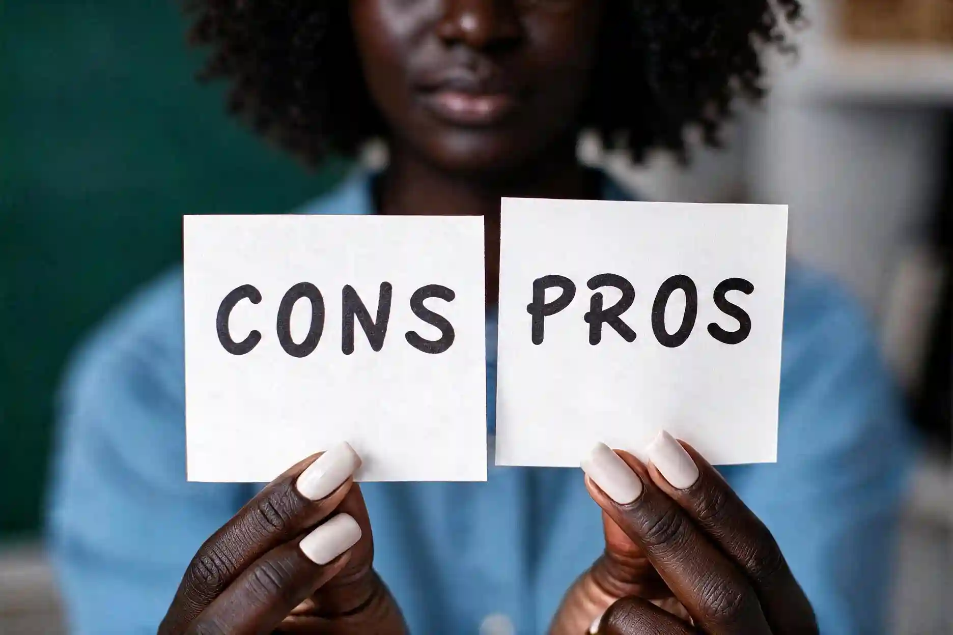Black woman in blue shirt holding Cons and Pros signs