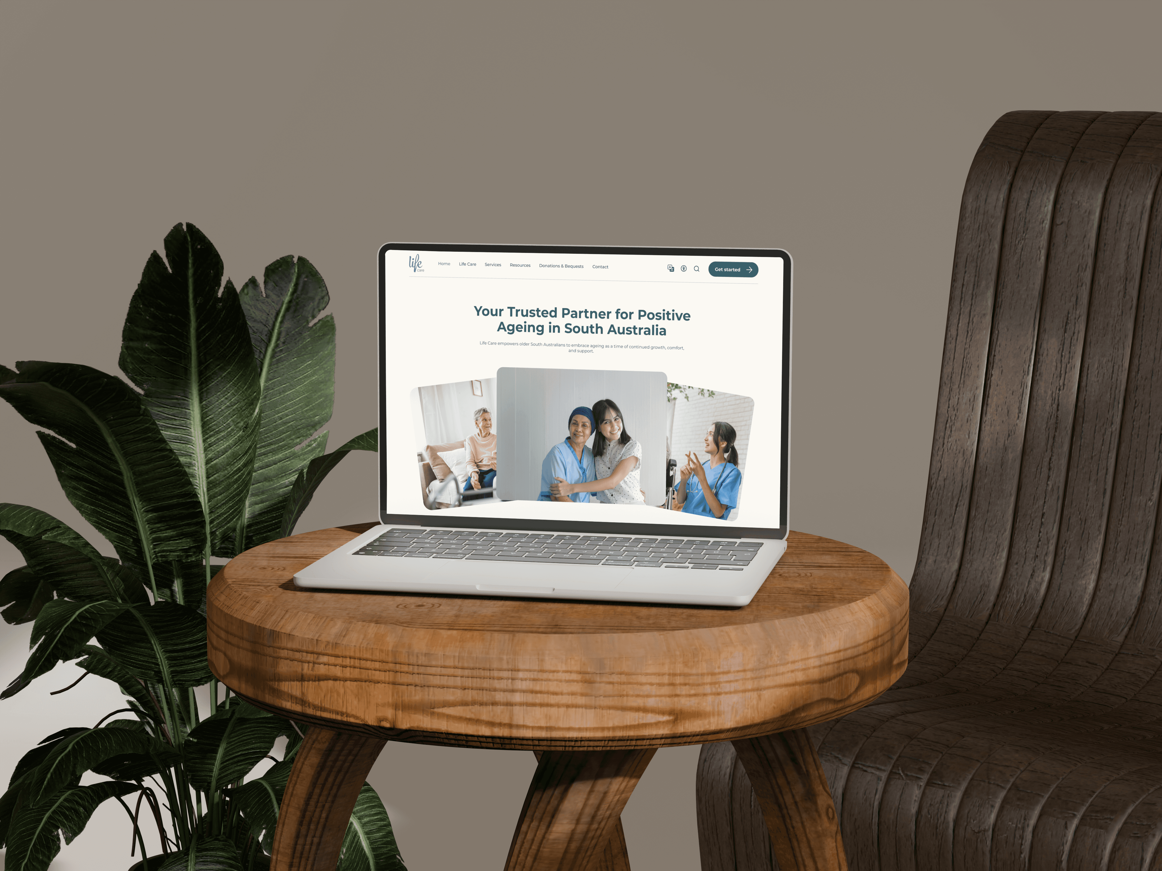 An open laptop sitting on a wood stool next to a plant