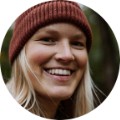 Lauren, 36, smiling outdoors in forest setting wearing winter beanie for customer testimonial