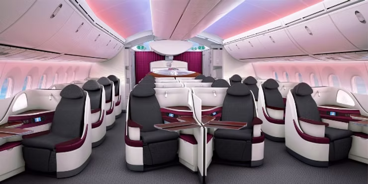 Qatar Airways Qsuite cabin showcasing the revolutionary quad-seating configuration with burgundy accents, privacy dividers, and spacious lie-flat seats.