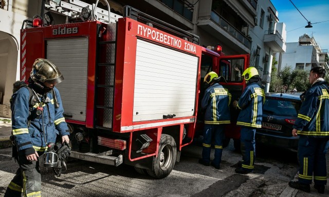 Fire crews assist two elderly residents after a kitchen fire in the village of Milia near Metsovo.