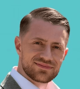 Smiling person in a white shirt against a dark background.