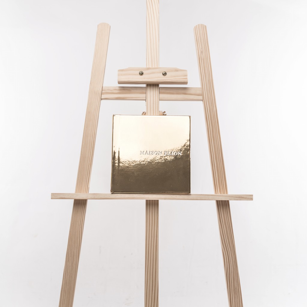 Golden Fine Art wedding album embossed with “Maison Elion” — photographed on a minimalist wooden easel against a pure white backdrop. Album de mariage Fine Art doré embossé “Maison Elion” — photographié sur un chevalet en bois minimaliste, sur fond blanc épuré.
