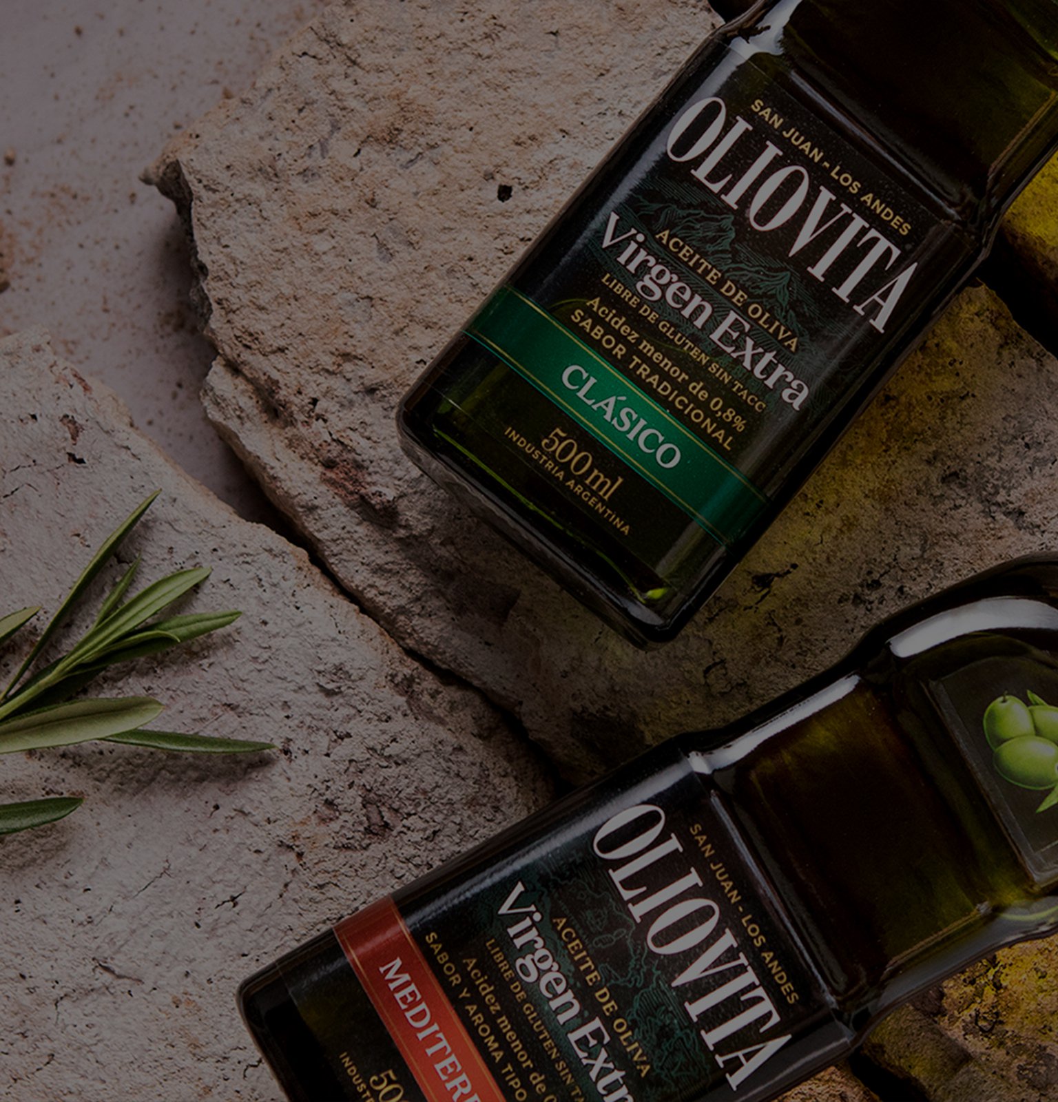 Bottles of OLIOVITA extra virgin olive oil on a textured surface, with one labeled "Clásico" and the other "Mediterráneo."