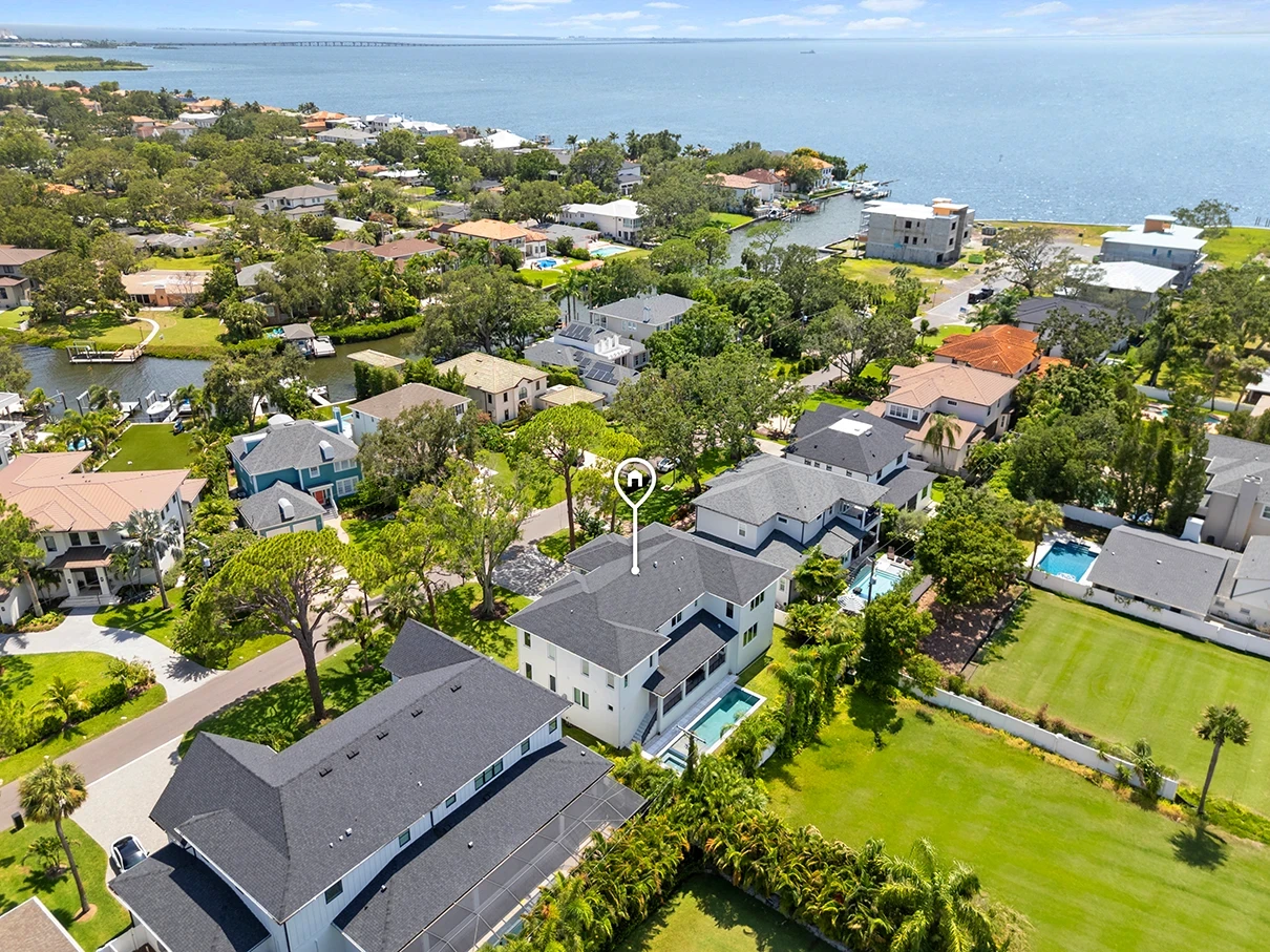 Aerial drone photo of a South Tampa home near the waterfront, with pool, canals and Tampa Bay in the distance