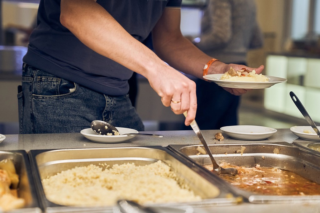 Volunteer serving hot food from canteen trays at a day centre