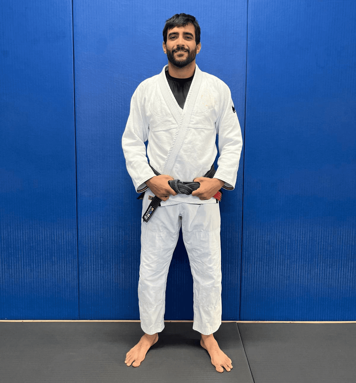 Maria Elisa Thimoteo smiling in her gi, hands folded in front of a gradient backdrop