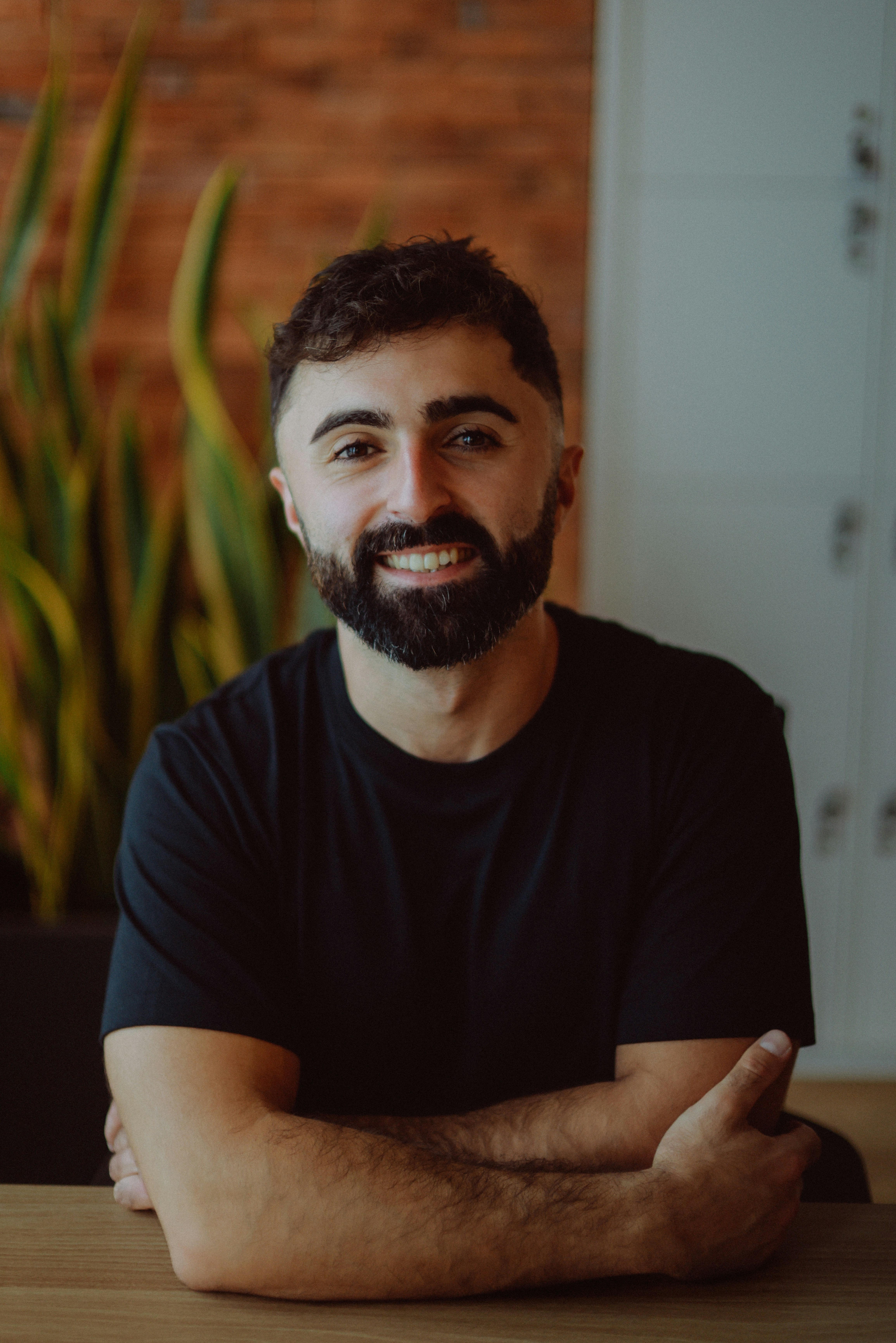 A smiling man with a beard in a black t-shirt.
