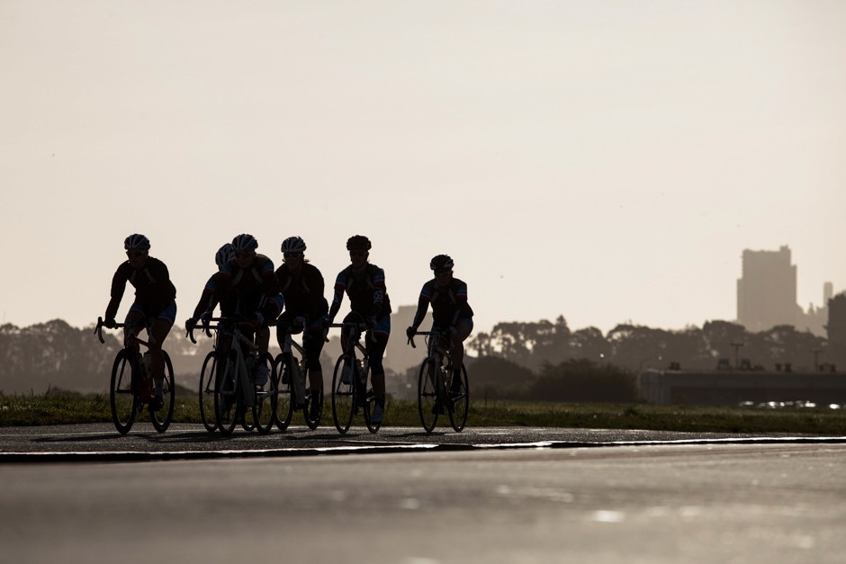 A greyscale image of cyclists at dusk.