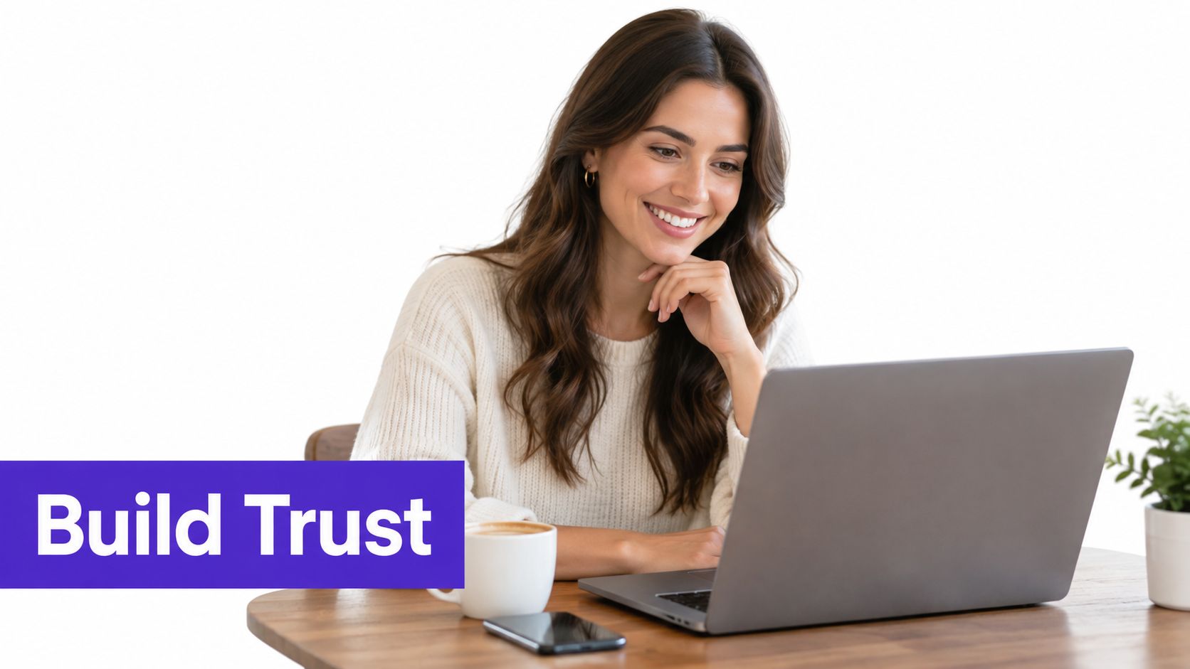 A smiling woman sits at a wooden table while looking at her laptop screen to build trust.