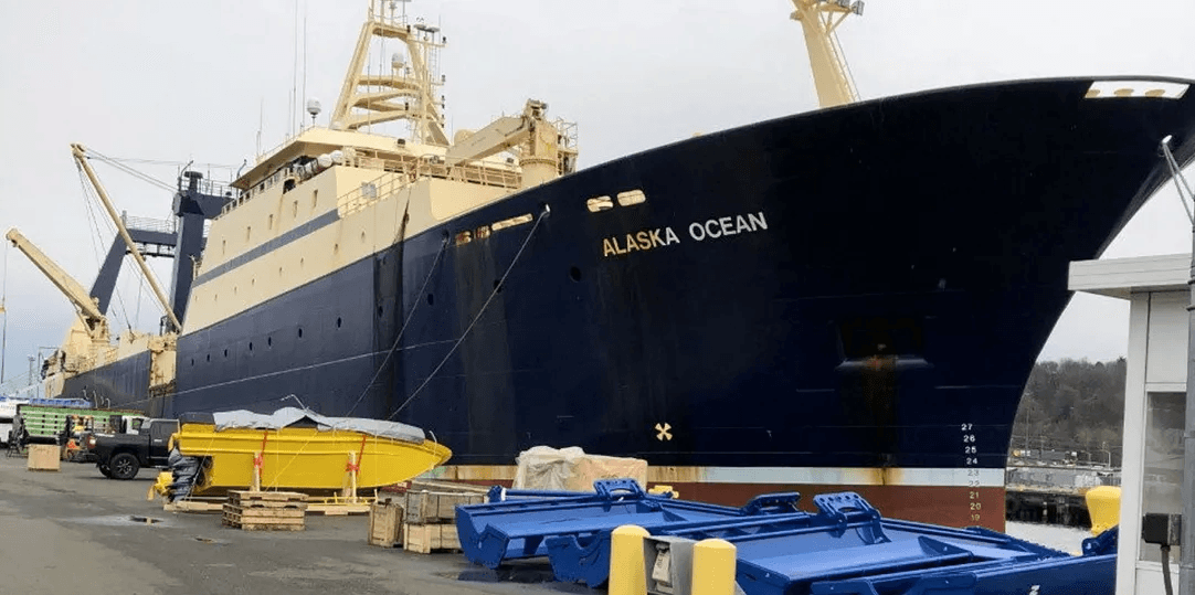 Marine vessel docked at port with industrial support systems visible.