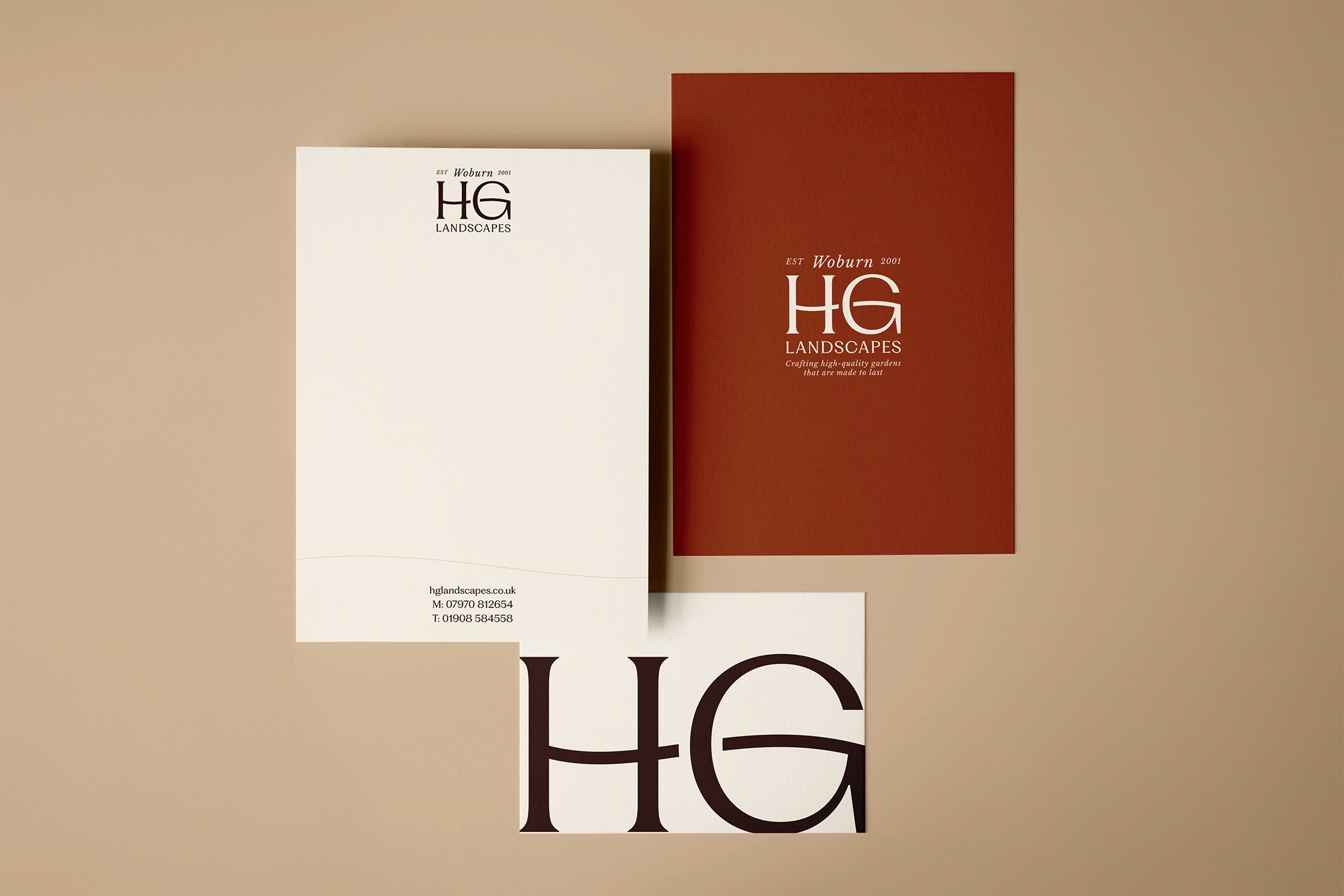 Two elegantly designed books, one white and one rust-colored, display the initials "HG" in a minimalist setting.