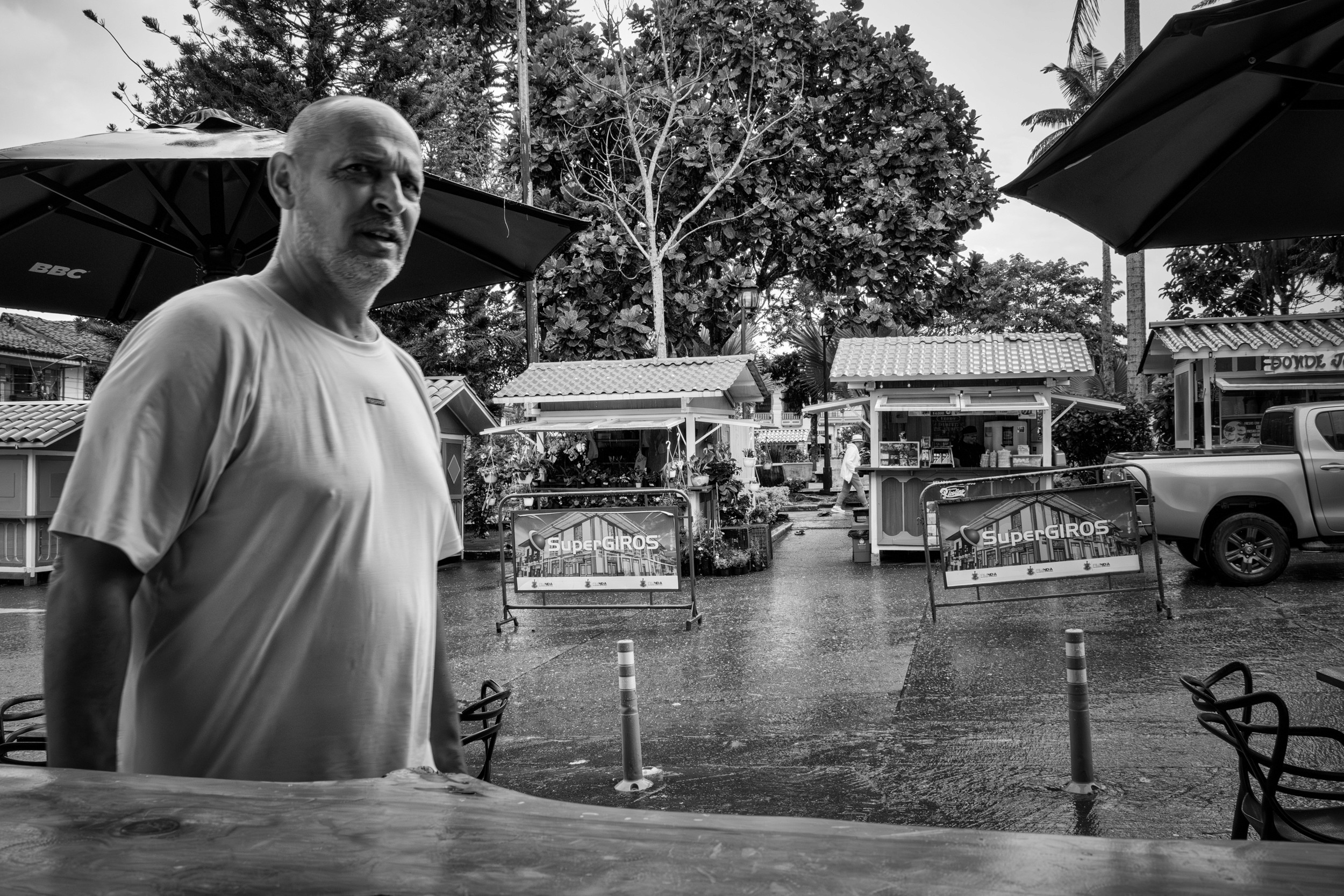 Rainy street scene with people passing by a bar window.