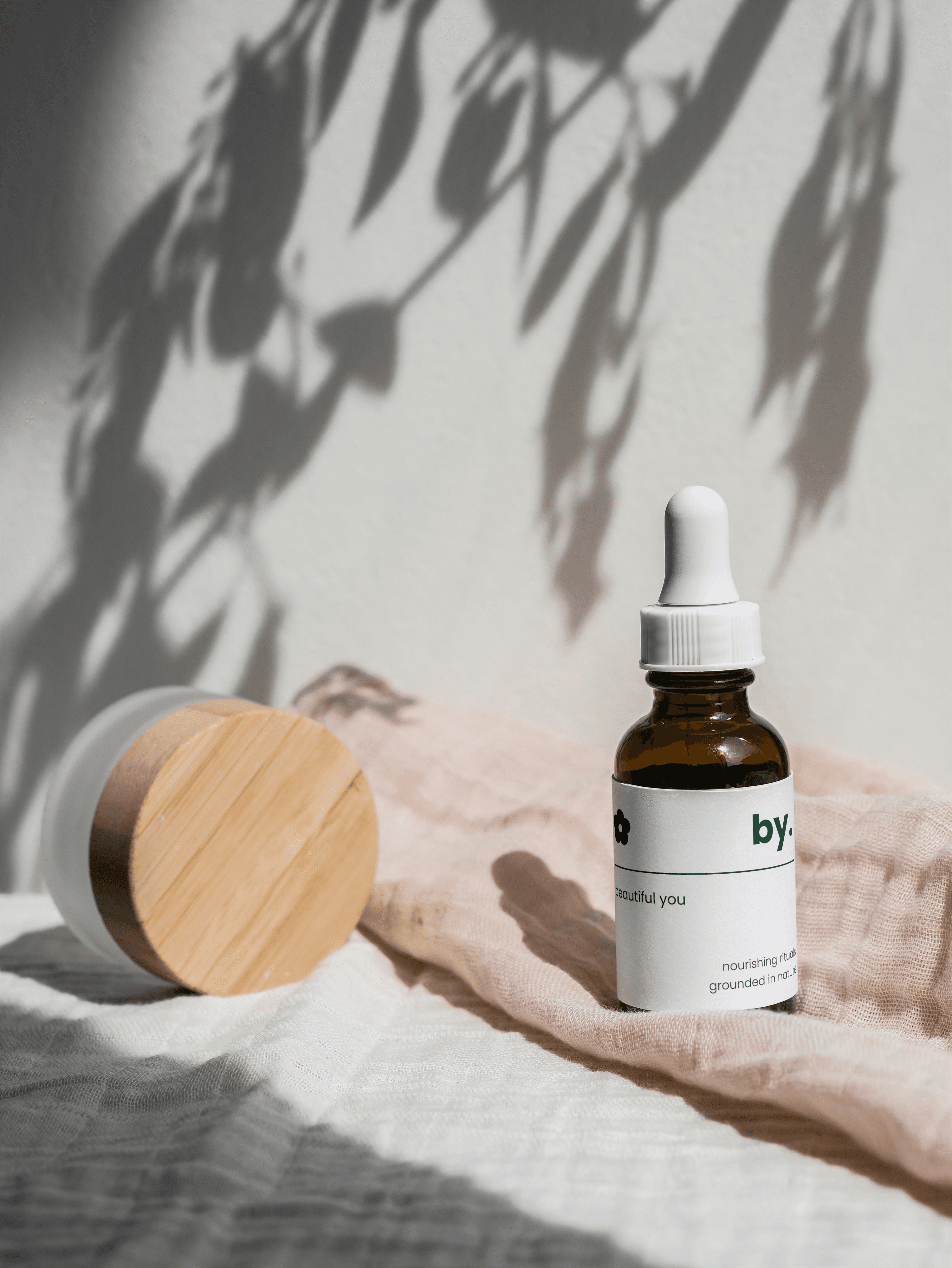 skincare dropper bottle and container staged on a light pink and white cloth
