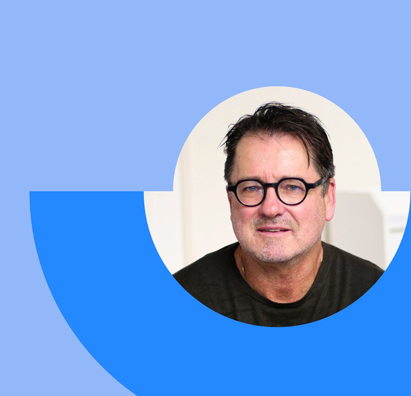 Portrait of Peter Giesen with a neutral background and blue abstract design elements.