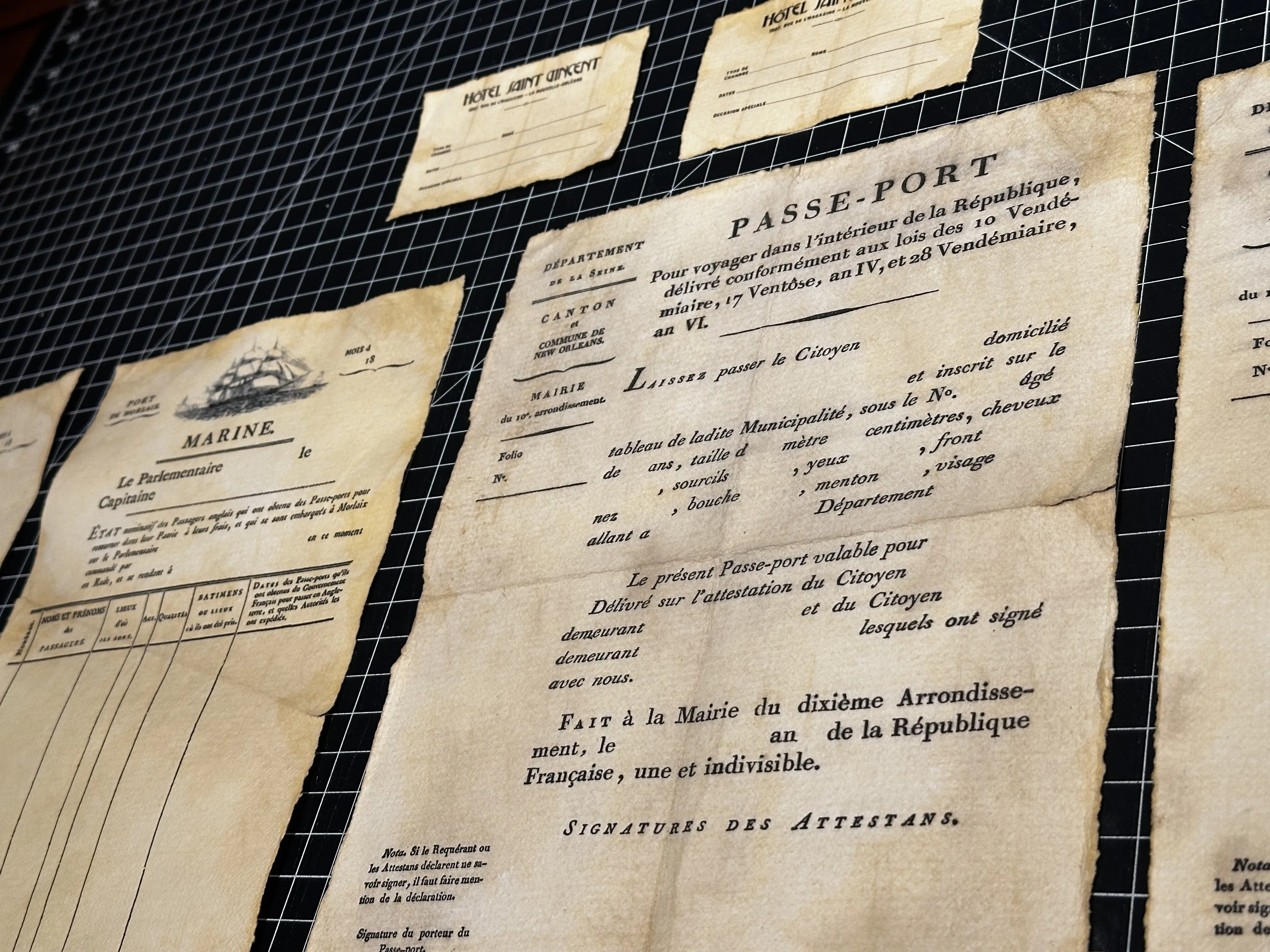 The image showcases an array of historical documents displayed on a grid background, featuring a prominent aged passport titled "PASSE-PORT," illustrating intricate designs and detailed text, epitomizing vintage document design. Rob Harrigan Design. Rob Harrigan. 