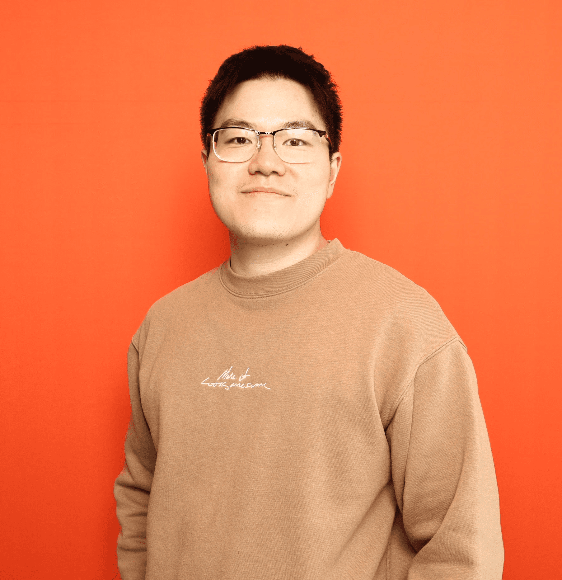 A young person with long, wavy hair sits in front of a plain background, looking directly at the camera.