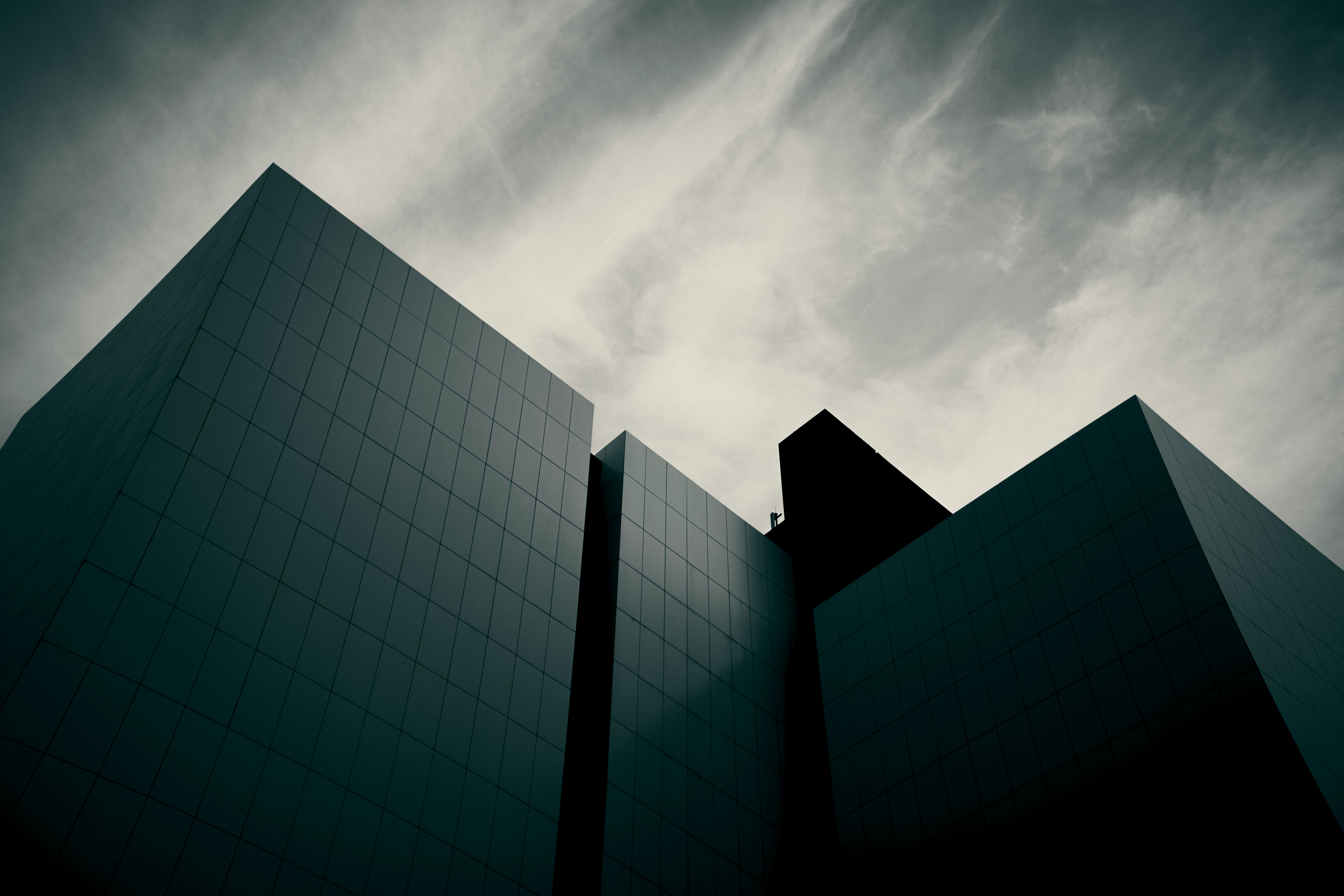 Dark, angular modern buildings against a dramatic cloudy sky.