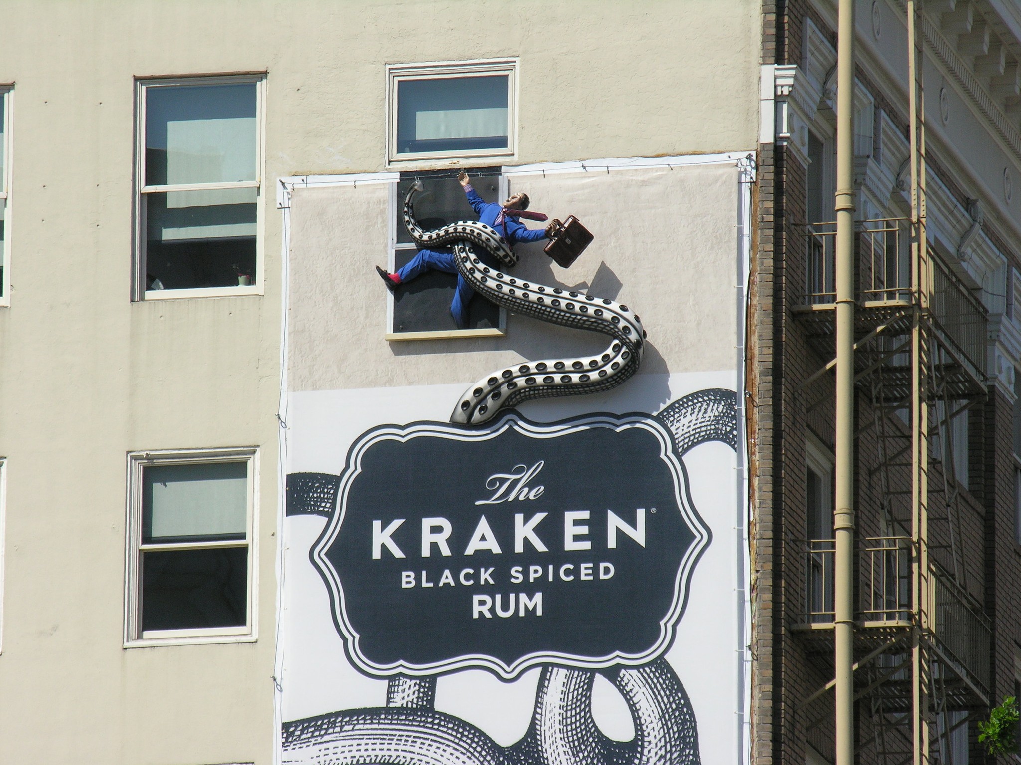 Picture of a billboard showing the Kraken, with 3D tentacle elements holding mannequins protruding from the billboard. 