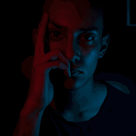 Man with hand on his face, lit by red and blue light, symbolising emotional conflict and the value of therapy from HeadHealth.