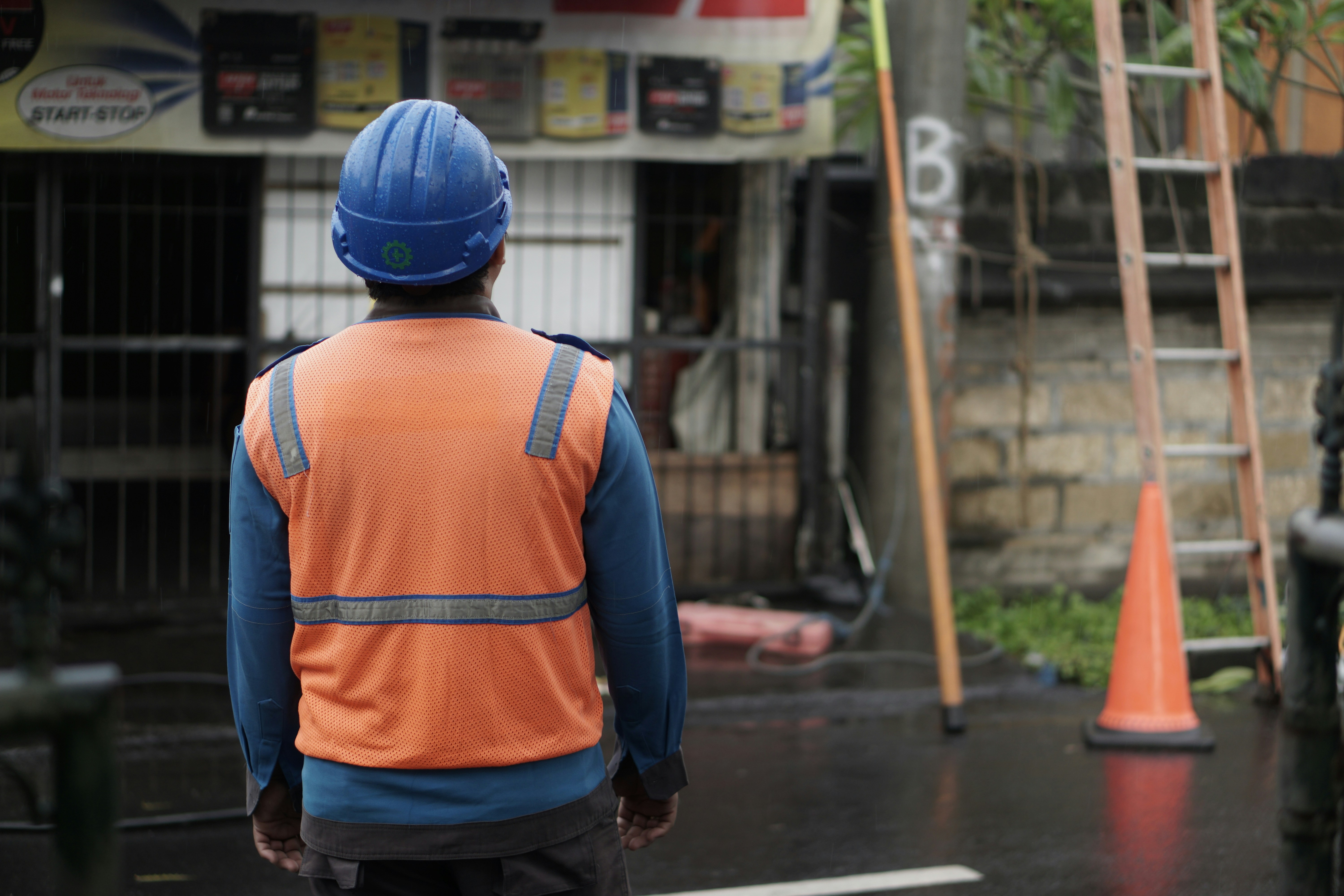 a man in an orange vest and a blue helmet