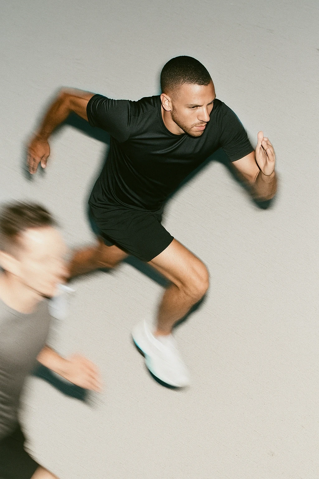 Zwei Männer sprinten Seite an Seite – Symbolbild für maximale Leistungsfähigkeit, Geschwindigkeit und natürliche Energieunterstützung im Alltag