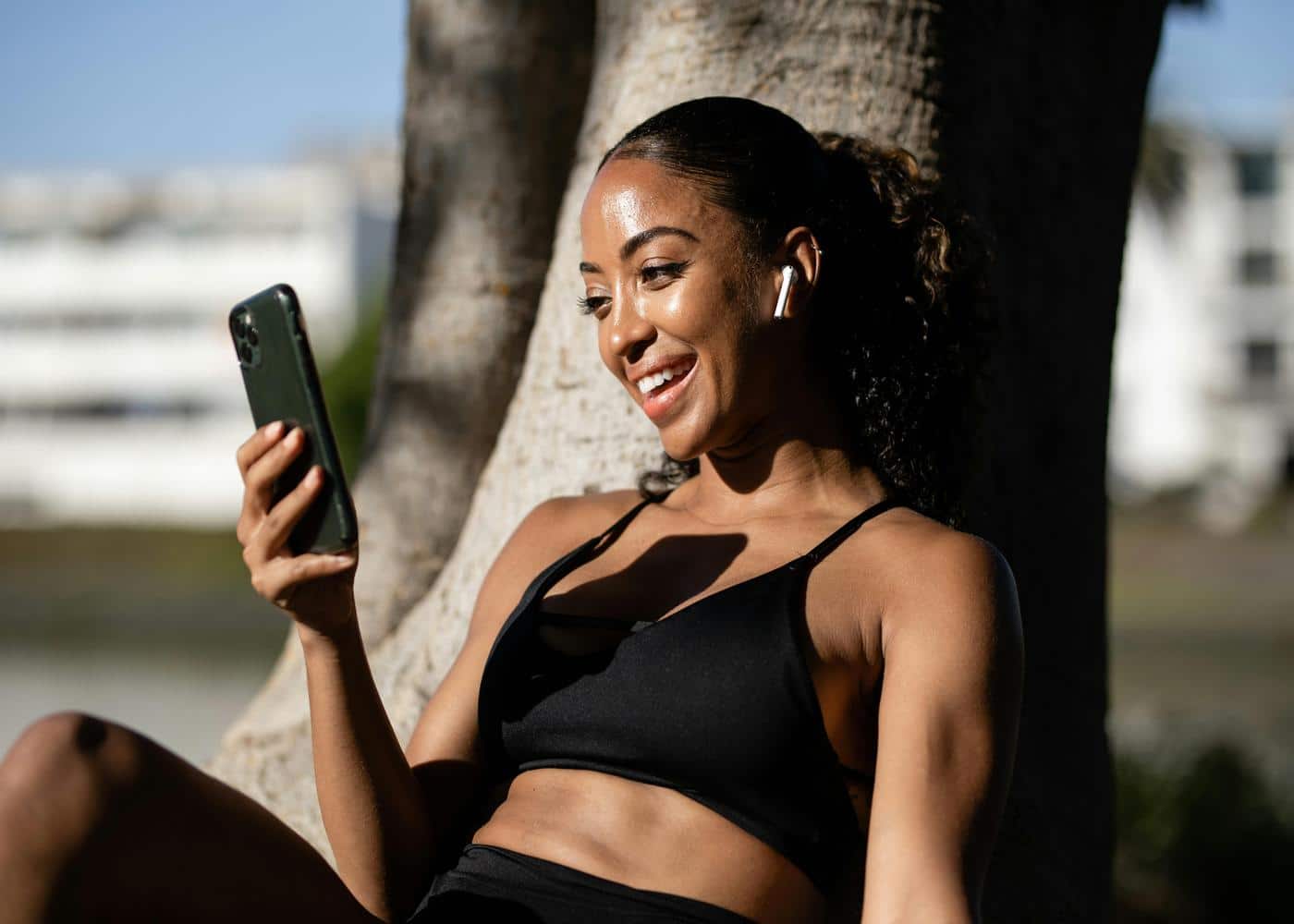 Smiling woman sitting outdoors looking at smartphone